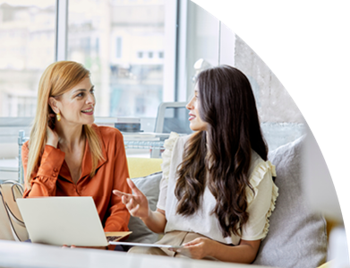 Zwei Frauen arbeiten an einem Tisch mit Laptop und Dokumenten