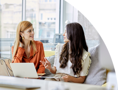 Zwei Frauen arbeiten an einem Tisch mit Laptop und Dokumenten