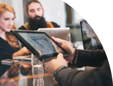 Mehrere Personen sitzen in einem Meeting. Der Fokus liegt aber auf der Ansicht eines eingeschalteten Tabletts.