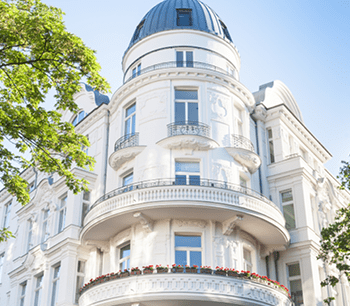 Schöne Immobilie mit Balkon vor blauem Himmel und einer alten, charmanten Fassade.